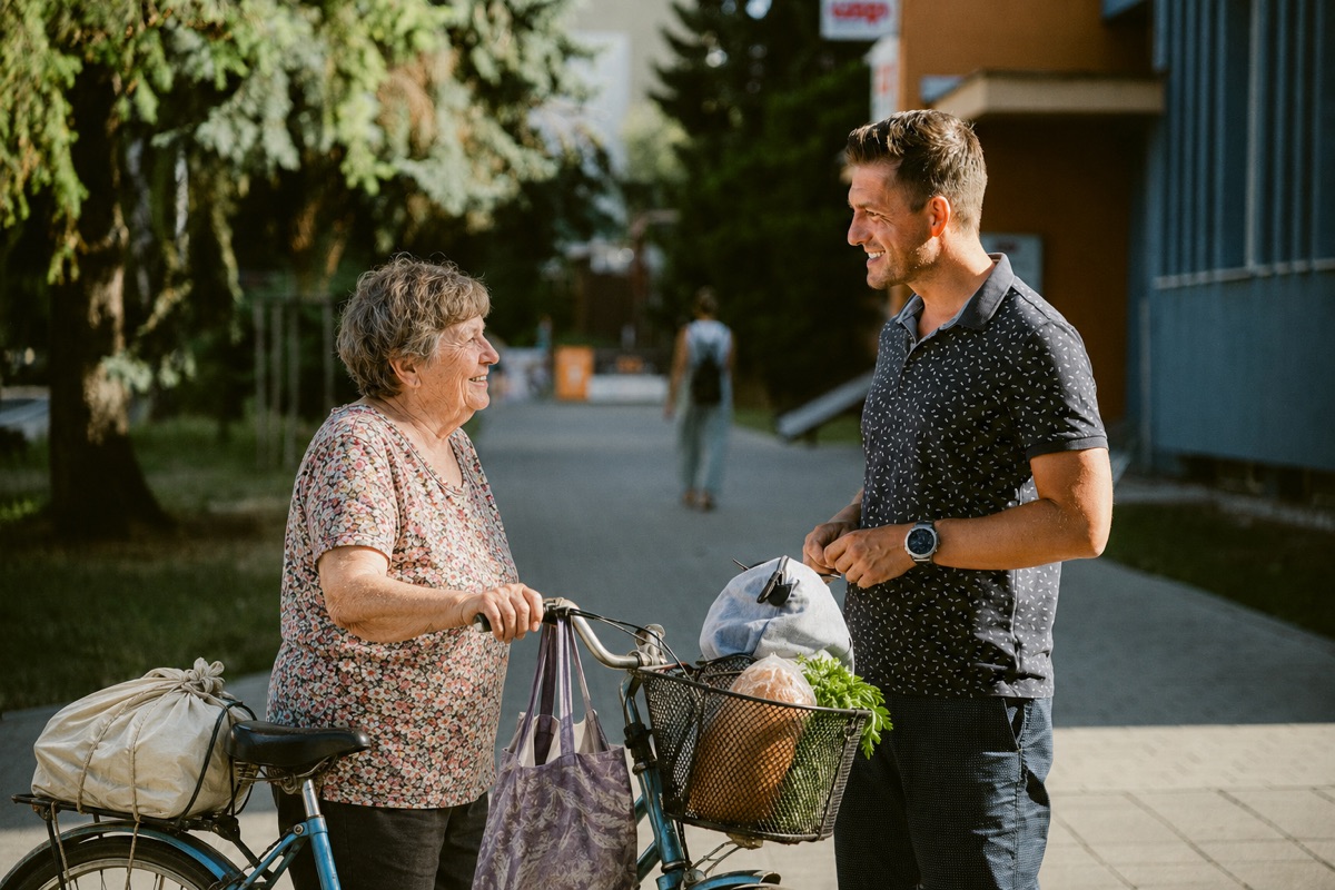 Roman Krištofík sa rozpráva s obyvateľkou Senice, ktorá vedie bicykel s nákupom