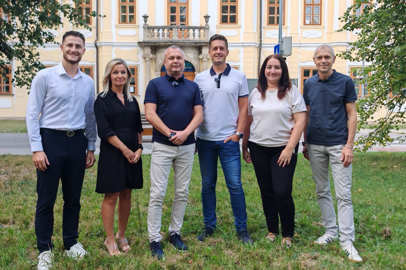 Šesť ľudí z iniciatívy Spoločne za zmenu stojí vedľa seba na tráve pred historickou budovou v Senici